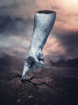 Stone human hand stuck in the desert in cloudy day