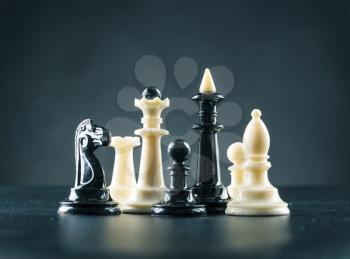 Chess figures on the table over black