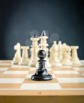 Black pawn standing in front of the white chess team