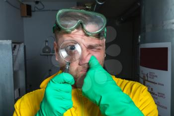 Funny man wearing protective outerwear suit in the lab with magnifier