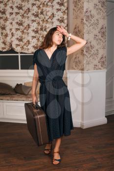 Young woman in black dress waiting for a journey. Retro style suitable for travel concept.