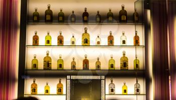 Bottles of alcohol on backlit shelves at a pub or bar. Luxury alcohol collection on hotel counter.