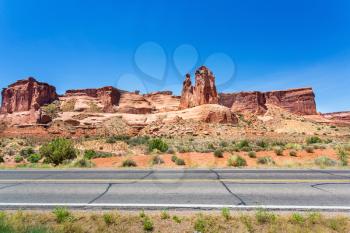 Asphalt road against sandstone mountains and skyline in Arches National Park.