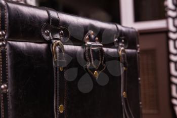 Black vintage suitcase leather texture. Old style bag clasp, buckle and belt closeup