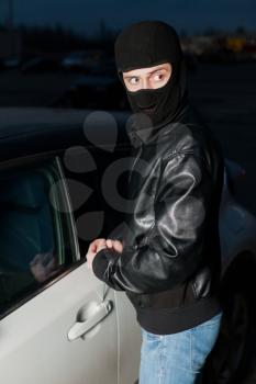 Male thief hands trying to open car door with screwdriver. Carjacker unlock vehicle. Carjacking danger