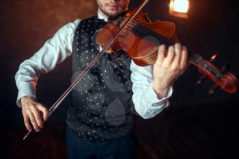 Portrait of male fiddler playing classical music on violin. Violinist man with musical instrument