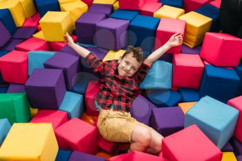 Little boy having fun with soft colorful cubes in childrens entertainment center. Happy childhood