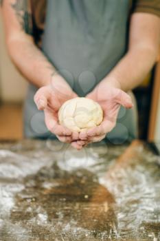 Homemade pasta cooking, male hands with dough. Man preparing spaghetti on wooden kitchen table