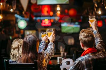 Group of football fans with scarf and ball watching match and drinks beer in sports bar. Tv broadcasting, young friends leisures in pub, favorite team wins