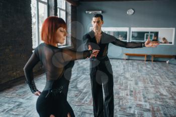 Dancers in costumes on ballrom dance training in class. Female and male partners on professional pair dancing in studio