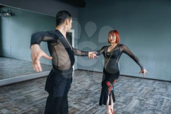Dancers in costumes on ballrom dance training in class. Female and male partners on professional pair dancing in studio