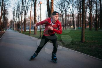 Roller skater rides by sidewalk in city park. Male rollerskater leisure