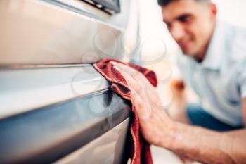 Car exterior polishing on carwash station. Man rubbing vehicle bumper with automobile polish