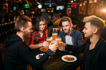 Group of friends having fun in a sport bar and drinks beer, happy football fans