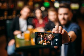 Fun friends makes selfie on phone camera in a sport bar, happy leisure of football fans