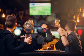 Three men watches football on TV in a sport bar, happy leisure of fan company