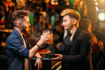 Two men at the bar counter raised their glasses with beer for the victory in game  in a sport pub, happy leisure of football fans