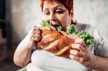 Fat woman eats sandwich, overweight and bulimic. Unhealthy lifestyle, obesity