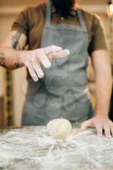 Fresh pasta cooking, chef in apron makes dough. Man preparing spaghetti on wooden kitchen table