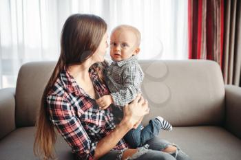 Young mother plays with little male child indoor. Mom and son happy together at home, togetherness