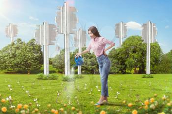 Woman watering keys sticking out of the ground like plants, green meadow on background. Idea concept
