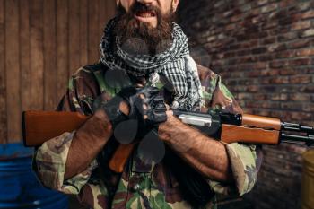 Cruel terrorist with a grin holds a kalashnikov rifle closeup, male mojahed with weapon. Terrorism and terror concept