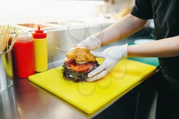 Chef prepares burger, fast food cooking. Hamburger preparation process, fastfood