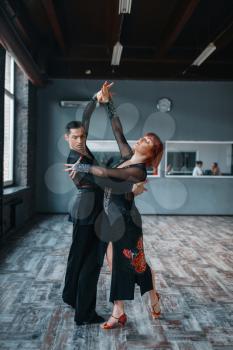Couple in costumes on ballrom dance training in class. Female and male partners on professional pair dancing in studio