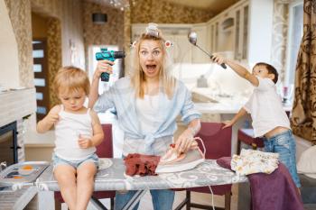 Housewife with kids having a good time on the kitchen. Woman with children playing at home together. Female person with daughter and son fooling around in their house