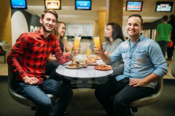 Friends drinks juice and eats pizza in bowling club, active leisure, healthy lifestyle, bowling game