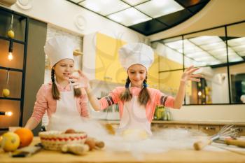 Two little girls chefs prepared dough, cookies preparation on the kitchen, funny bakers. Kids cooking pastry, children cooks preparing cake