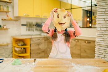 Little girl chef made a funny face out of dough, cookies preparation on the kitchen, funny baker. Kids cooking pastry, child cook, children preparing cake