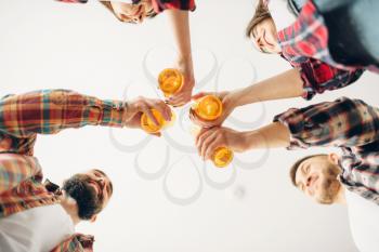 Smiling friends clink bottles with beer, bottom view, home party. Good friendship, group of people leisures together. Cheerful company celebrate the event