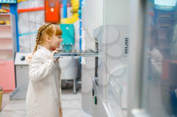 Little girl in uniform playing doctor in analysis laboratory, playroom. Kid plays medicine worker in imaginary hospital lab, profession learning, childish dream