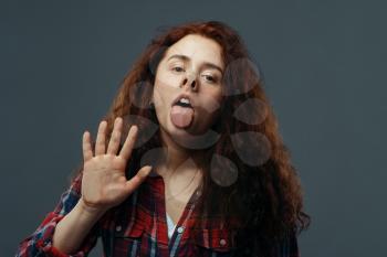 Young woman's face and hand crushed on transparent glass. Female person standing at the showcase with uncomfortable looking, humor, emotion expression