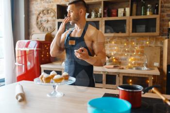 Nude man in apron cooking dessert with cream on the kitchen. Naked male person preparing breakfast at home, food preparation without clothes