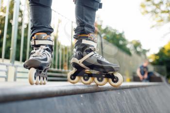 Roller skating, male skater standing on ramp. Urban roller-skating, active extreme sport outdoors