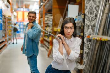 Couple plays with chain in hardware store. Male and female customers look at the goods in diy shop