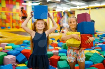 Two little girls playing with soft cubes, playground in entertainment center. Play area indoors, playroom