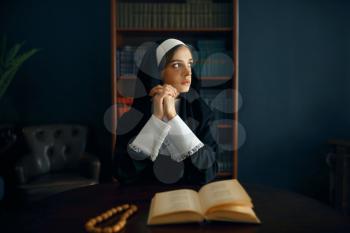 Young nun in a cassock prays crossed her arms. The sister in the monastery, religion and faith, religious person