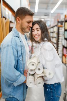 Young couple choosing wallcovering in hardware store. Male and female customers look at the goods in diy shop