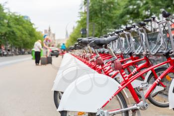 Bicycle rental, Europe, bike rent parking. Urban eco transport, human powered vehicle, row of red cycles, nobody