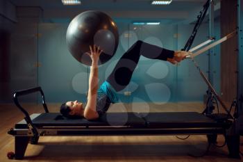 Slim girl in sportswear, pilates training with ball on exercise machine in gym. Fitness workuot in sport club. Athletic female person, aerobics indoor, body stretching