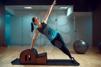 Slim girl in sportswear on pilates training on mat in gym, flexibility. Fitness workuot in sport club. Athletic female person, aerobics indoor, body stretching