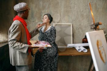 Portrait painter prepares female model in art studio. Male artist standing at his workplace, creative master in workshop