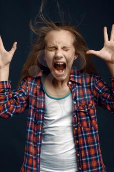 Little girl shouting in studio, developing hair effect. Children and wind, kid isolated on dark background, child emotion
