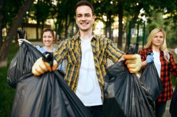 Volunteers holds full plastic trash bags in park, volunteering. Male person cleans forest, ecological restoration, eco lifestyle, garbage collection and recycling, ecology care, environment cleaning