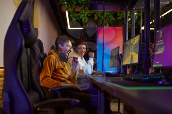 Two young gamers play in game club. Virtual entertainment, e-sport tournament, cybersport lifestyle. Male person leisures in internet cafe