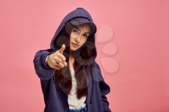 Young smiling woman in hoodie, pink background, emotion. Face expression, female person looking on camera in studio, emotional concept, feelings