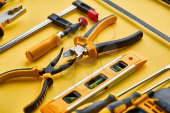 Professional workshop instrument, yellow background, nobody. Carpenter tools, builder equipment, screwdriver and piles, hacksaw and level